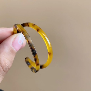 Detailed close-up of retro C-shaped resin earrings with classic tortoiseshell pattern