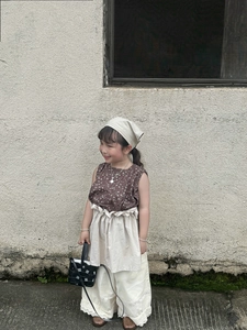 Close-up of a child wearing a vintage floral outfit with a black woven handbag