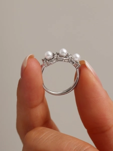 Detail of adjustable silver steel ring with three white pearls held by fingers