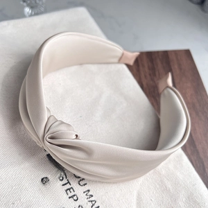 Detail of elegant beige satin headband with top knot design and silky fabric texture