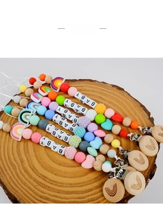 Macro view of beechwood pacifier clips with rainbow silicone beads and baby lettering
