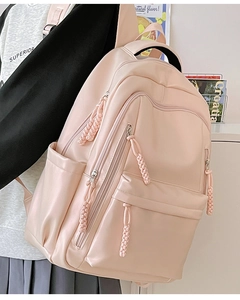 Detailed close-up of pink PU leather backpack with multiple zipper pockets and woven pullers