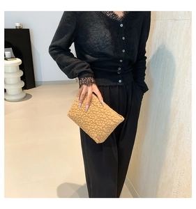 Close-up of beige quilted fabric with elegant 3D floral embroidery on a cosmetic bag