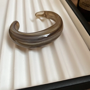 Close-up of wide acrylic cuff bracelet with brown marble texture on a display tray
