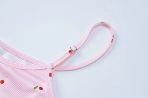 Détail des bretelles réglables sur une robe en maille côtelée rose à motif de cerises