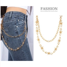 Detail of a gold multi-layer punk waist chain with star-shaped metal links on denim