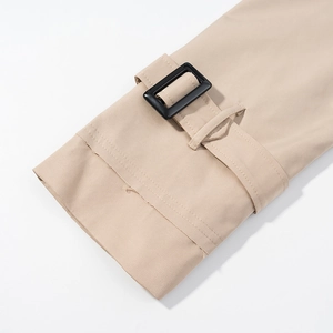 Detail of beige jacket cuff featuring adjustable strap and black square buckle fastener