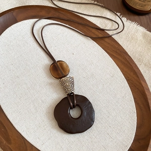 Detail of vintage wooden resin pendant on a dark tray with rustic linen background