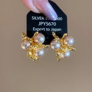 Close-up of golden firework-shaped pearl earrings with starburst lighting effect
