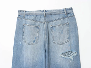 Dettaglio dei jeans azzurri con tasche posteriori e finiture vintage effetto usurato