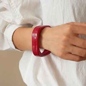 Close-up of a bold red resin geometric bangle on a wrist for a high-fashion summer look
