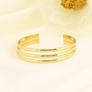 Detailed view of triple-layer gold stainless steel cuff featuring fine cartoon engravings