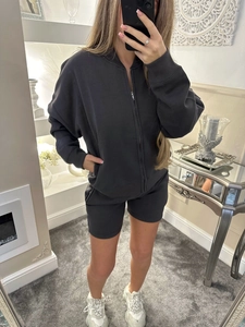 Close-up of charcoal grey sporty zip-up jacket and matching shorts on a model
