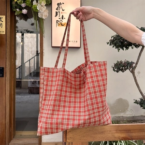 Detail of red and white gingham canvas tote bag with long shoulder straps in soft light
