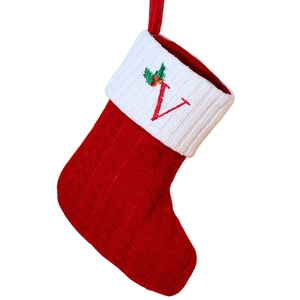 Red and white knitted Christmas stocking with embroidered letter V and green holly leaf decoration