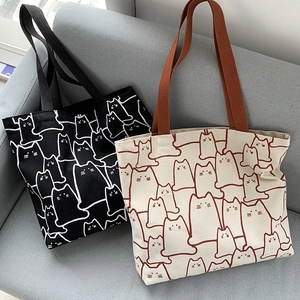 Detail of two canvas tote bags featuring cute minimalist cat patterns on a sofa