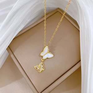 Dettaglio della collana farfalla dorata con madreperla e zirconi su scatola regalo beige