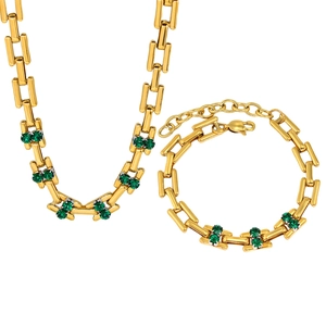 Detail of gold chain necklace and bracelet set with emerald green zircon gemstones