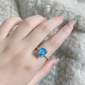 Detail of emerald cut aquamarine silver ring with pave diamonds on model's hand