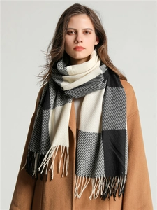 Detail of classic black white and grey plaid knit scarf with tassel fringe on model