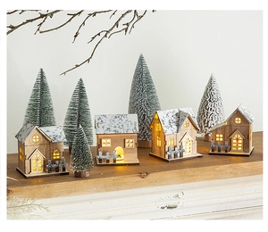 Detail of wooden Christmas house scene with warm LED lights and mini snowy trees