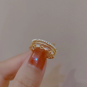 Three-piece ring set with pearls and zircons in warm gold finish worn on fingers