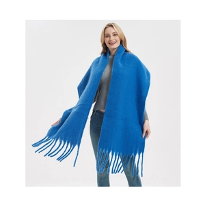 Detailed close-up of soft vibrant blue mohair knit scarf with fringe trim on female model