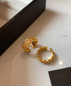 Detailed close-up of gold-plated crossover rings with sparkling cubic zirconia inlay