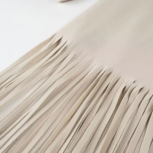 Dettaglio delle frange in finta pelle scamosciata beige e cuciture sul cappotto