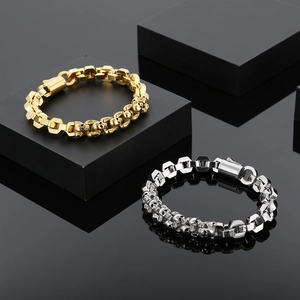 Detailed view of punk style gold and silver skull bracelets on black reflective base