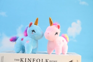 Dettaglio di peluche di unicorno blu e rosa con corna dorate e ricami a stella lucidi
