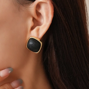 Macro shot of a geometric square leather earring with elegant gold trim worn by a model