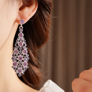 Detalle de pendientes largos de diamantes de imitación morados usados por una modelo