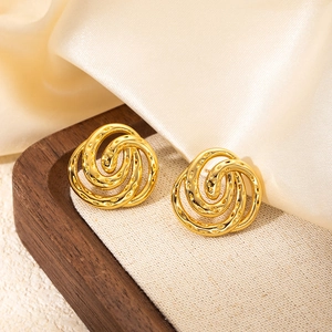 Macro detail of golden triple-layered spiral earrings with a hammered texture finish