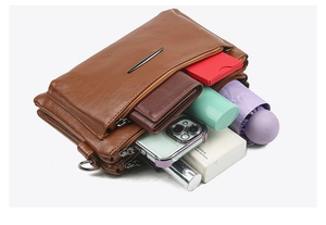 Brown leather crossbody bag with multiple zip compartments showing large storage capacity