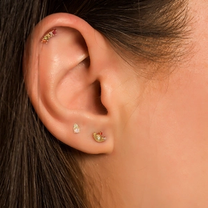 Close-up of gold helix ear piercing set with colorful zircon and opal gemstones