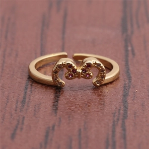Macro shot of gold adjustable butterfly ring with red rhinestones on dark wood