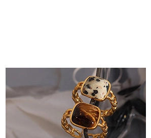 Macro shot of 18K gold plated chain rings with square natural stone inlays on white fabric