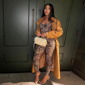 Street style view of leopard print jumpsuit paired with a camel wool coat and white bag