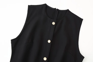 Close-up of black sleeveless midi dress with decorative gold buttons and round neckline