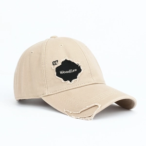 Macro detail of khaki baseball cap featuring distressed holes and Woodlise embroidery