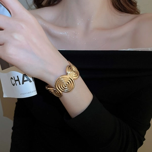 Detailed view of polished golden spiral flower cuff bracelet on a model wrist