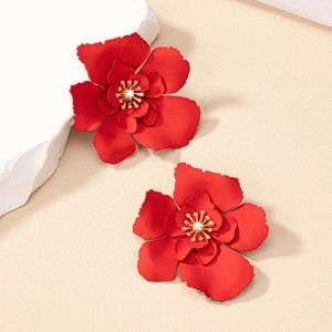 Close-up of red layered flower earrings with gold stamens and sparkling zircon center