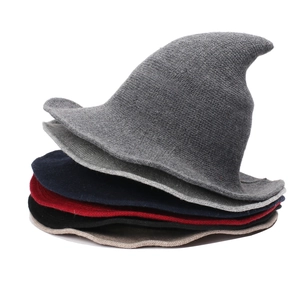 Stack of colorful knitted witch hats in grey, blue, red, black, and khaki on white background