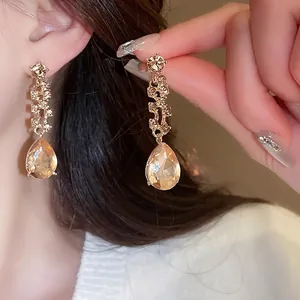 Elegant champagne teardrop crystal drop earrings on model with sparkling accents