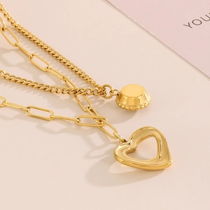 Dettaglio della collana a due strati in titanio dorato con pendenti a cuore e bottone