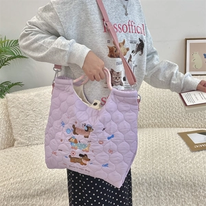 Close-up of a purple quilted tote bag with cute cartoon dog embroidery in a home setting
