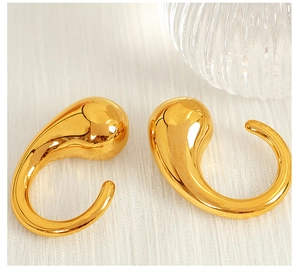Macro shot of minimalist gold-plated teardrop earrings with a glossy metallic finish