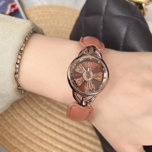 Rose gold women's watch with rotating dial and brown leather strap on wrist