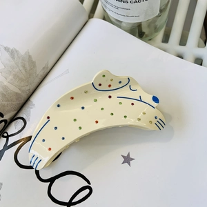 Détail d'une pince à cheveux dalmatien en acrylique avec strass colorés sur un livre